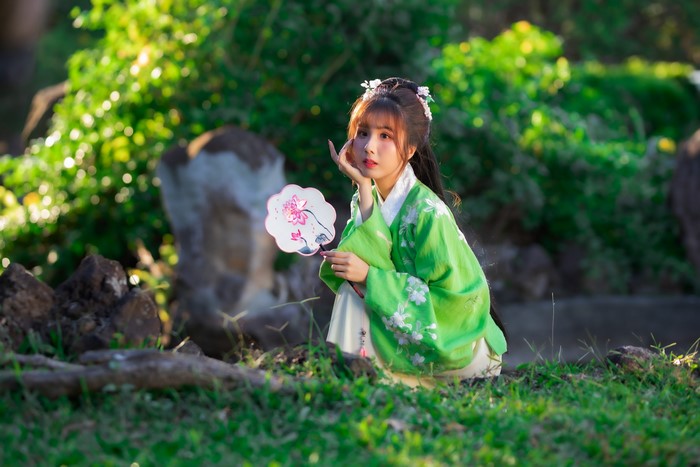 Asian woman in green kimono holding a fan