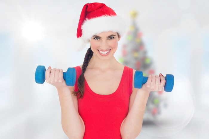 Woman in Santa hat lifting dumbbells