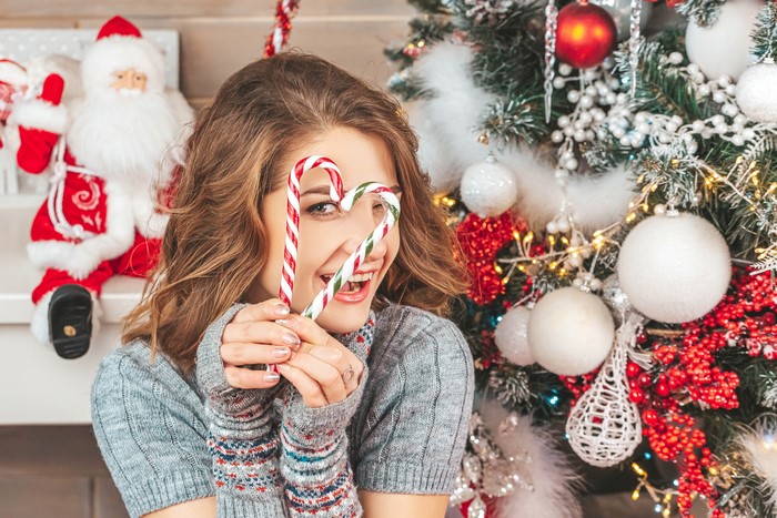 Woman holding candy canes in front of Christmas tree