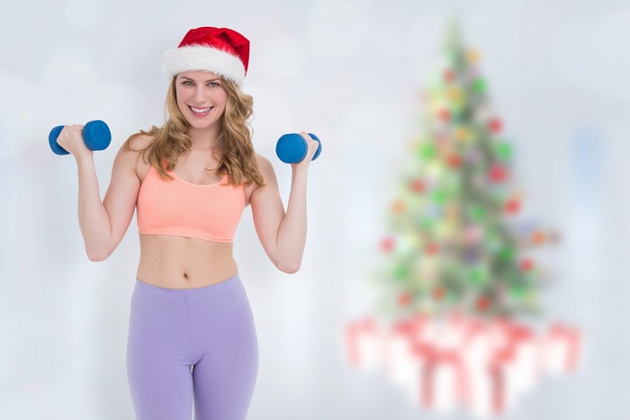 Woman in Santa hat lifting dumbbells