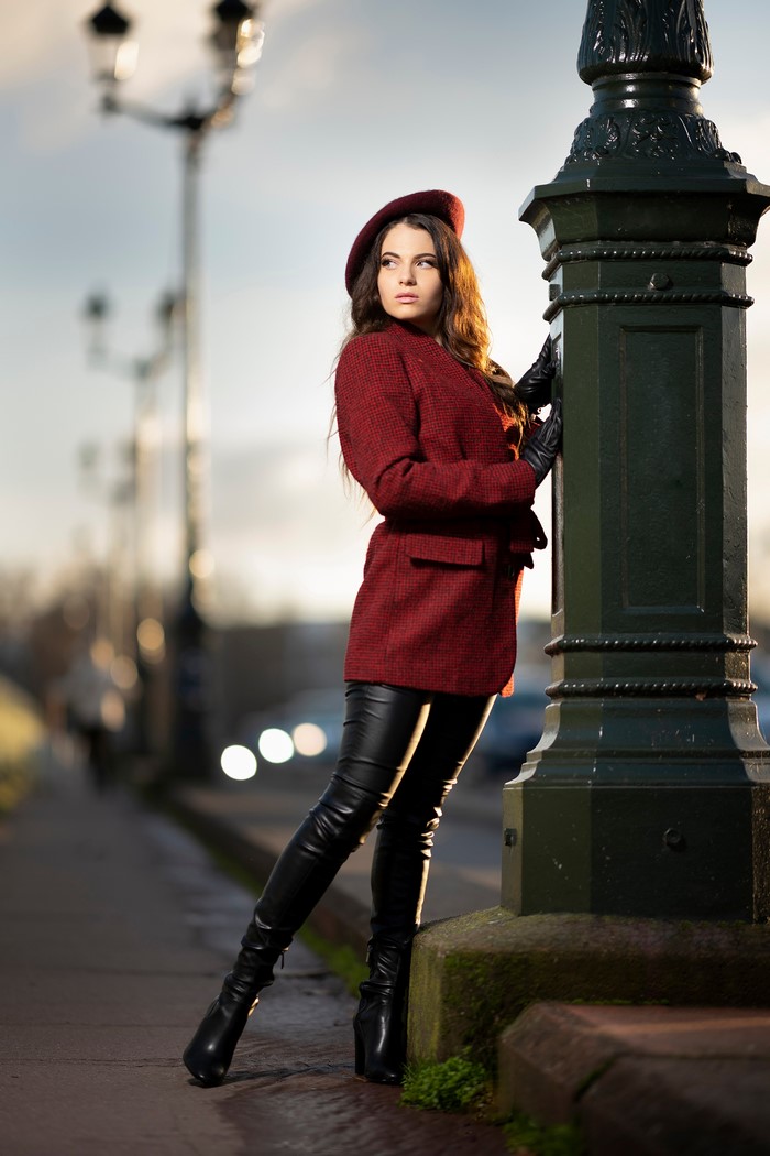Woman in red coat and beret posing by lamppost