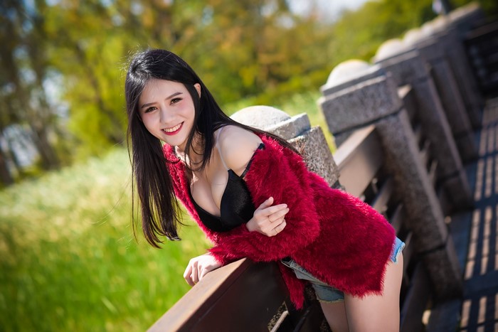 Brunette girl in red fur coat and black bra posing