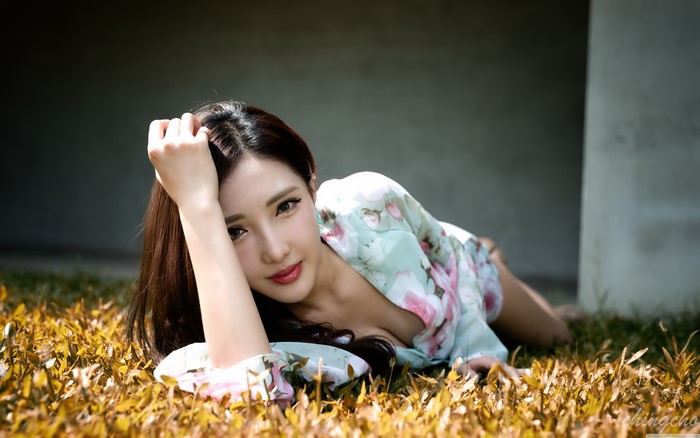 Asian woman with brown hair lying on grass