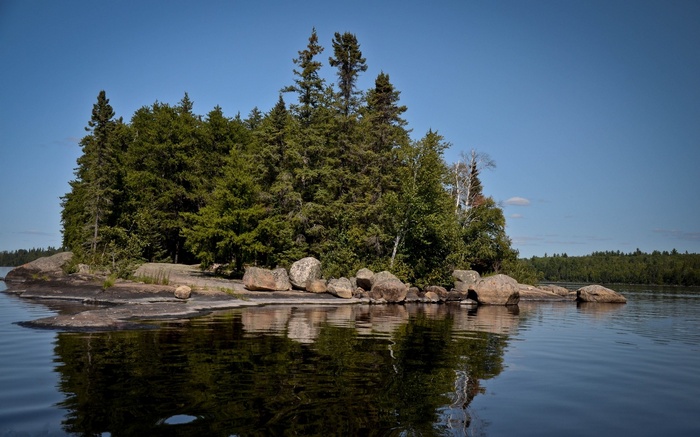 Island with trees and rocks reflected in water