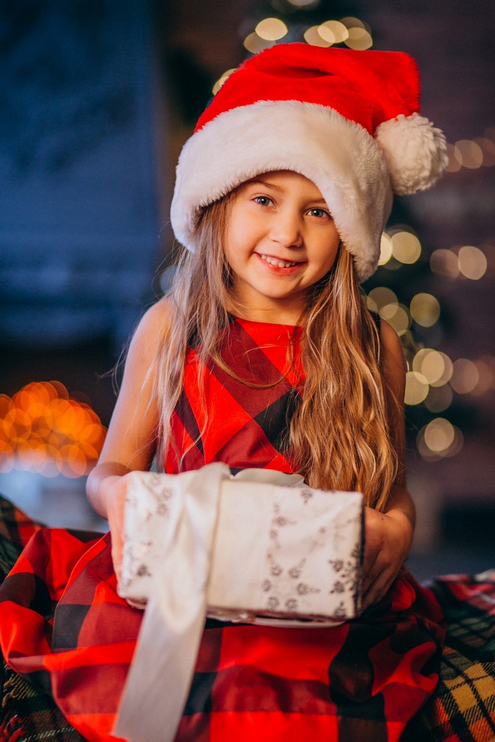 Girl in Santa hat holding a Christmas gift