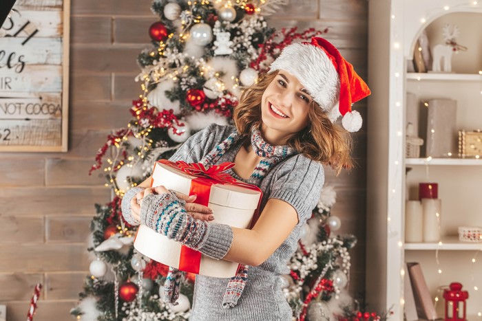Woman in Santa hat holding Christmas gifts