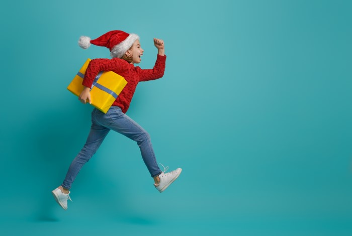 Girl in Santa hat running with Christmas gift