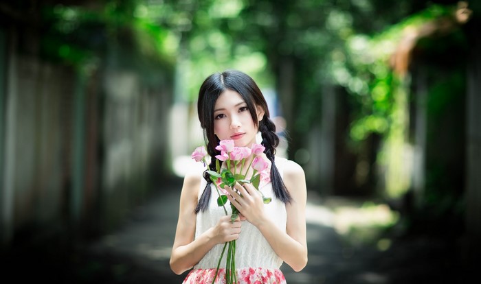 Brunette girl with pink roses and bokeh