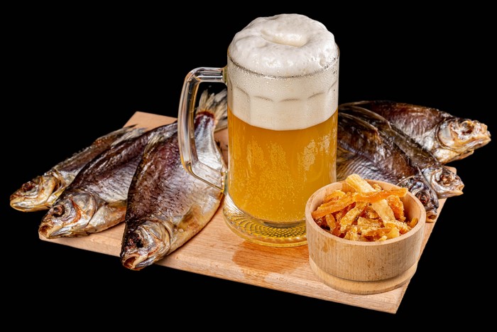 Beer with dried fish and snacks on a cutting board
