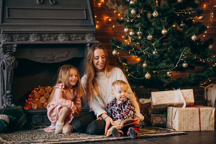 Mother reading to children by Christmas tree