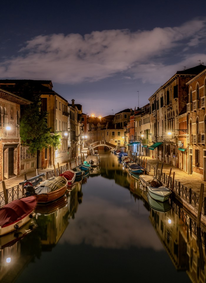 Venice canal at night with boats and buildings