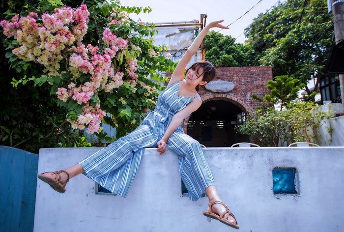 Asian woman in striped jumpsuit sitting by flowering trees