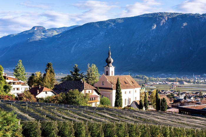Church and houses in Nalles, Italy with Alps mountains
