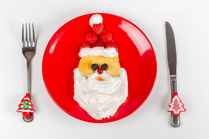 Santa Claus pancake with strawberries and whipped cream on a red plate