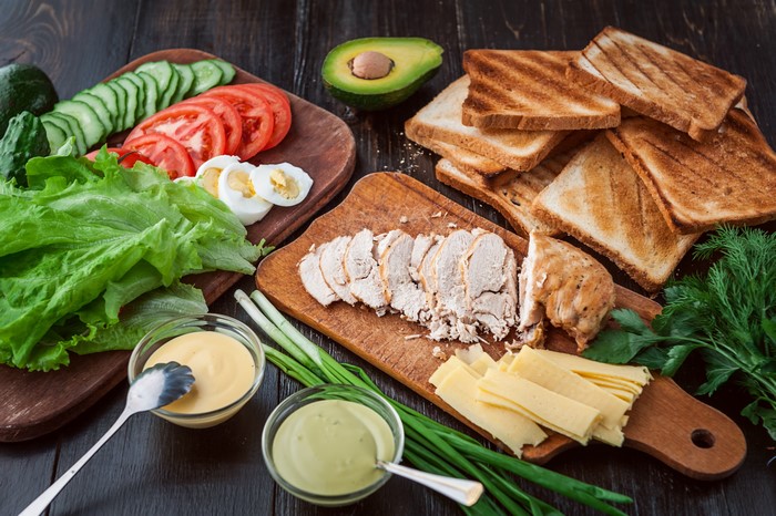 Sandwich ingredients: chicken, cheese, bread, vegetables, eggs, and sauces