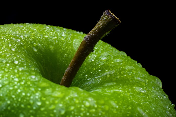 Green apple with water drops and stem