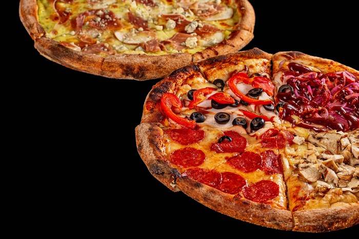 Two pizzas with various toppings on black background