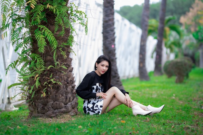 Brunette girl sitting by a palm tree