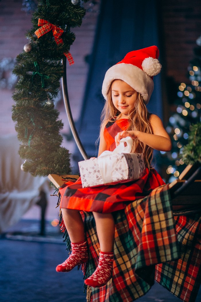 Girl in Santa hat opening Christmas gift