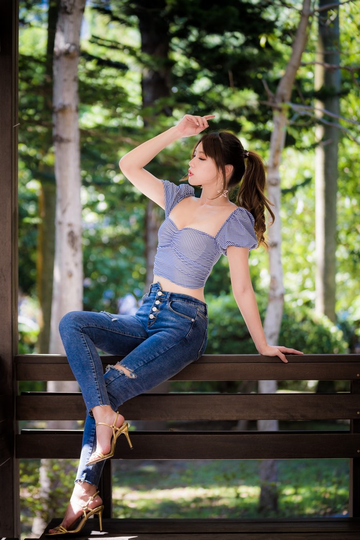 Asian Woman Sitting on Wooden Bench in Jeans