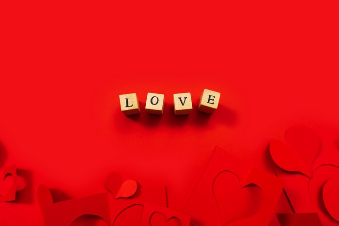 Wooden cubes spelling LOVE on red background with hearts