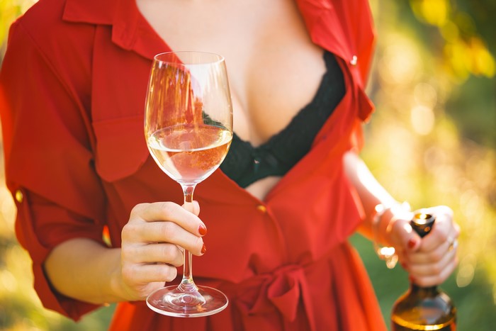 Woman in red dress holding wine glass and bottle