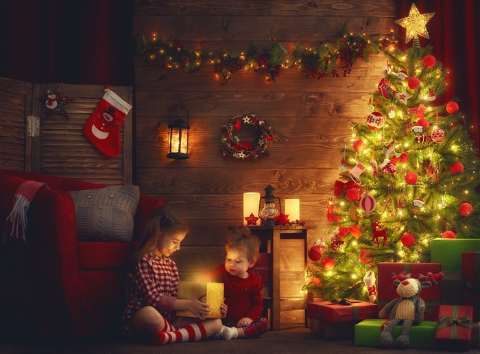 Children opening Christmas gifts by the tree