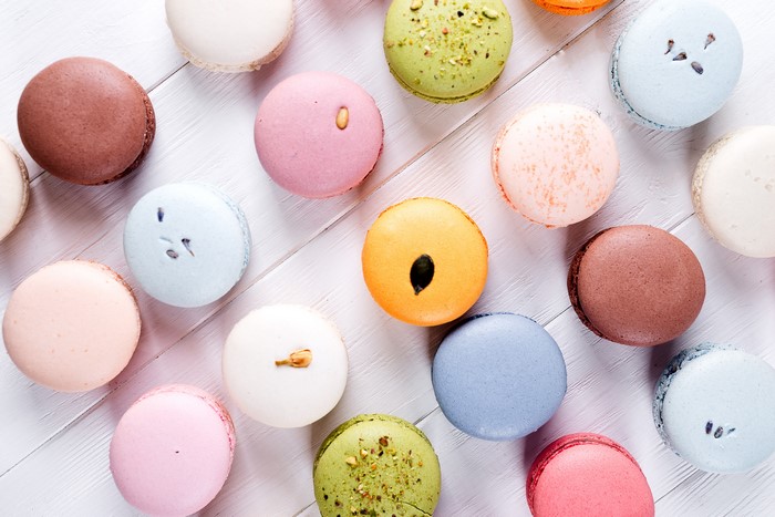 Assortment of colorful macarons on a white wooden surface