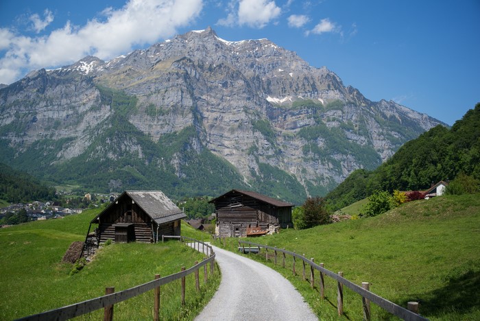 Wooden barns on a grassy hill with mountains in Glarus, Switzerland
