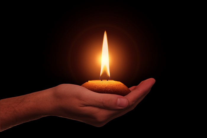 Hand holding a lit candle
