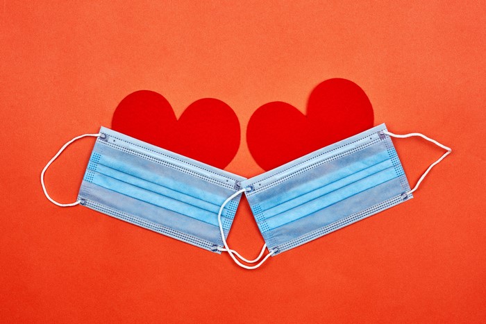 Two surgical masks and red hearts on orange background