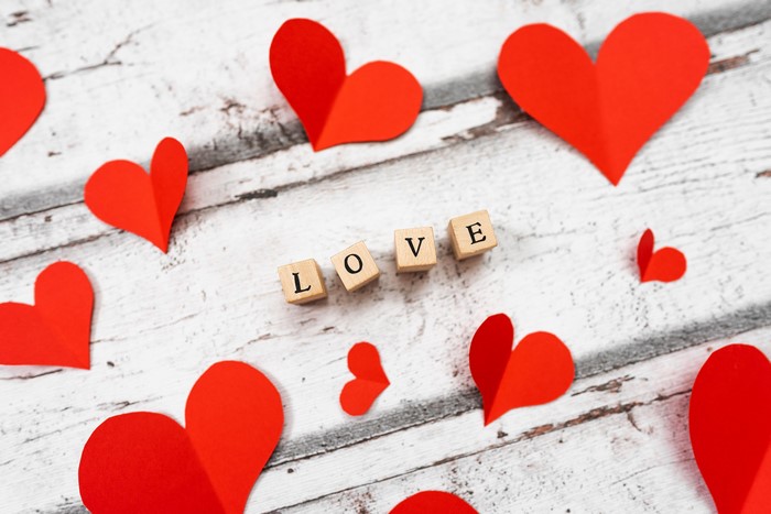 Love spelled with wooden blocks and red hearts on a wooden surface