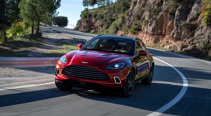 Red Aston Martin DBX driving on a winding road