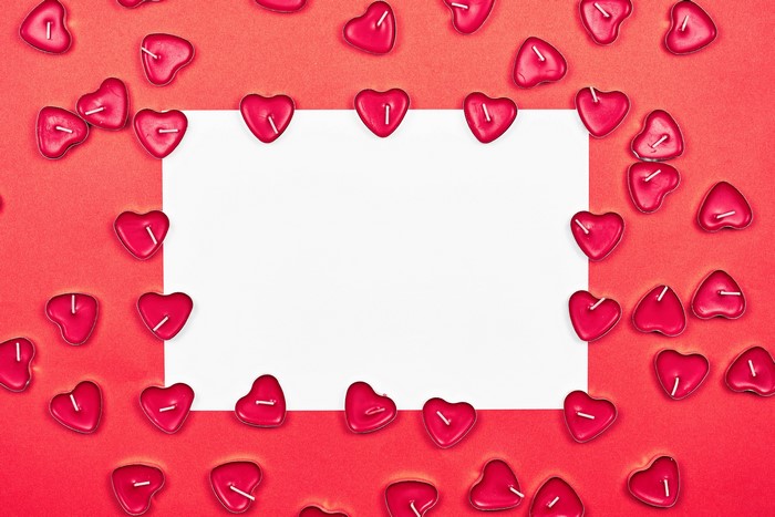 Heart-shaped candles around a blank white sheet of paper
