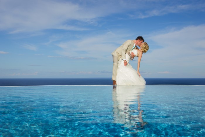 Bride and Groom kissing by infinity pool
