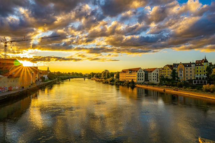Regensburg, Germany riverfront at sunset with buildings and clouds