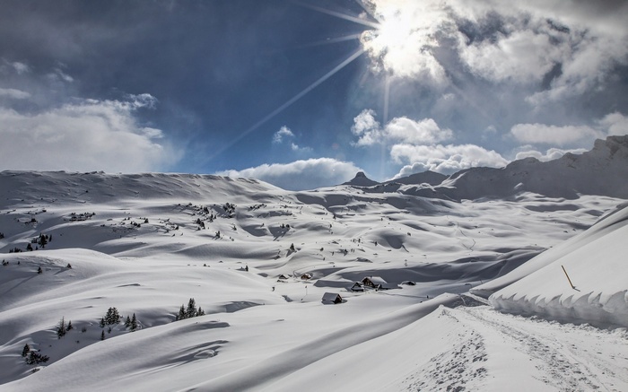 Snowy mountain landscape with sun and clouds