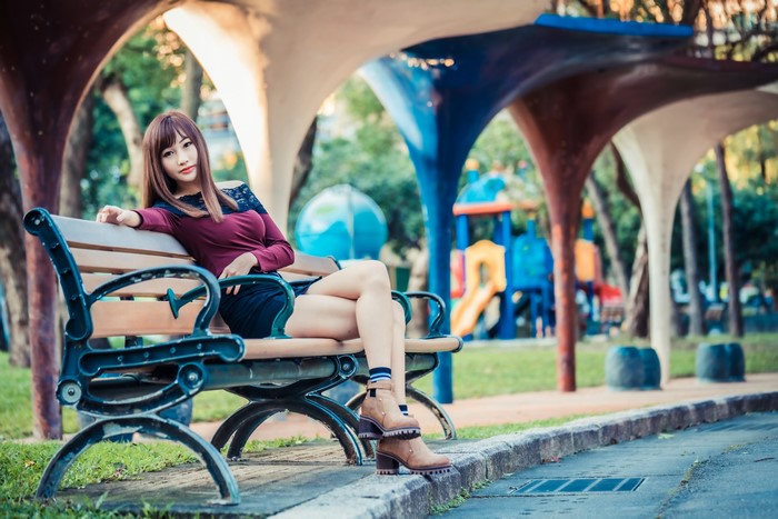 Asian woman sitting on a park bench