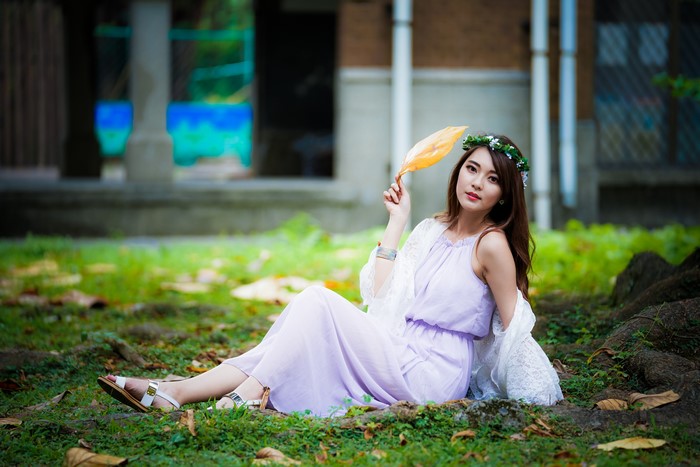 Asian woman with flower crown sitting in grass