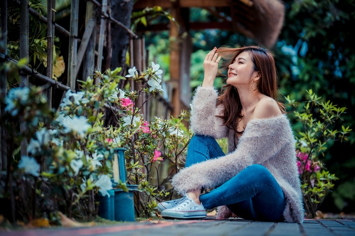 Asian woman with brown hair in jeans sitting