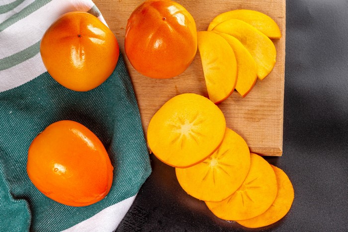 Persimmons on a cutting board with a towel