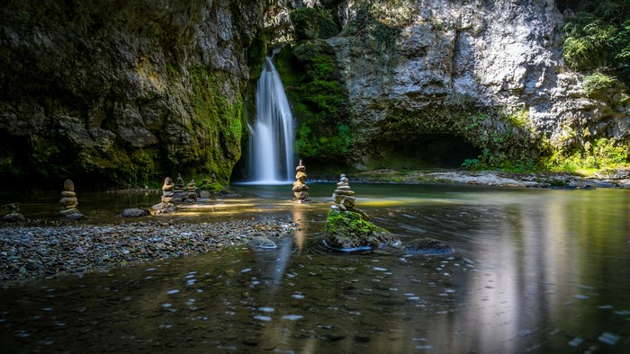 Waterfall with stacked stones in a mossy cave