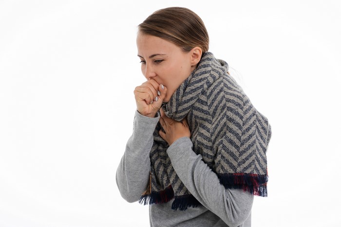 Woman with scarf coughing on white background