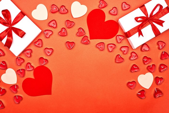 Valentine's Day gifts and heart-shaped candles on red background
