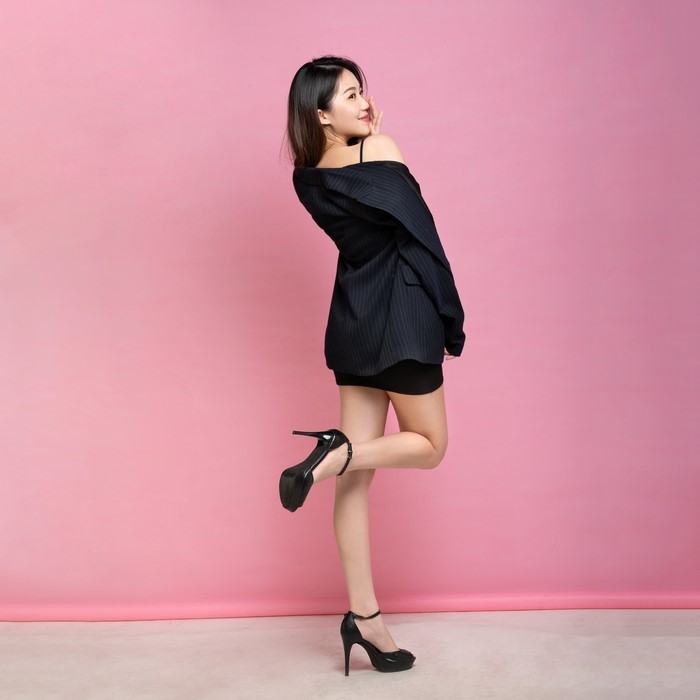 Asian woman in suit jacket and stilettos posing