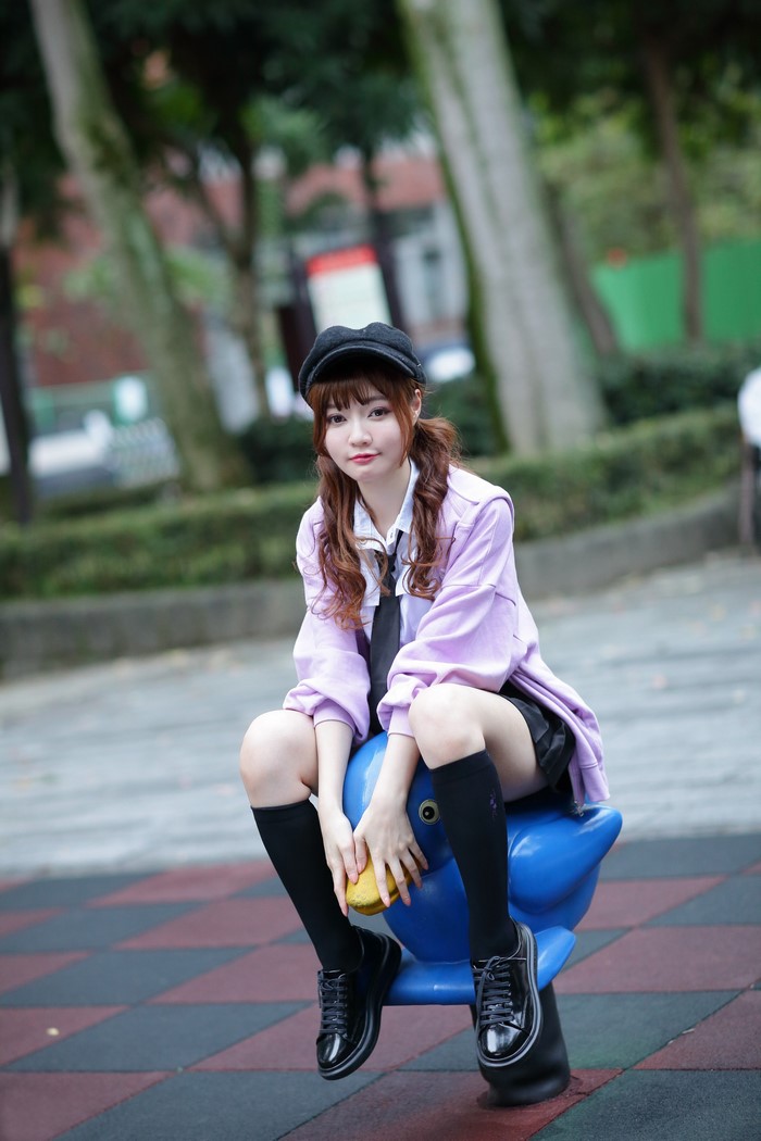 Asian girl in school uniform sitting on a playground toy