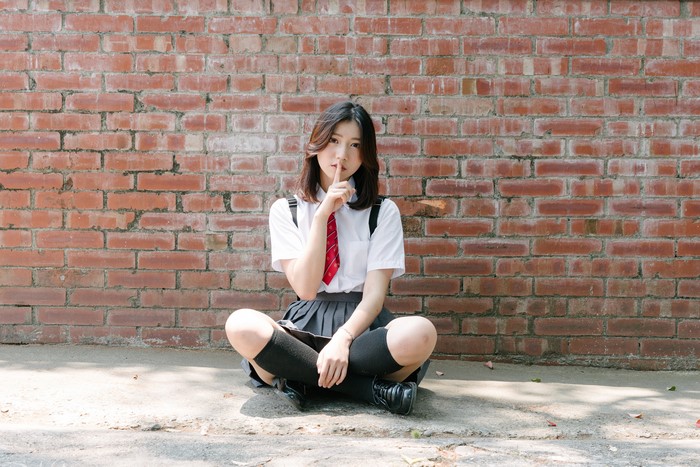 4K Asian Girl Sitting by Brick Wall