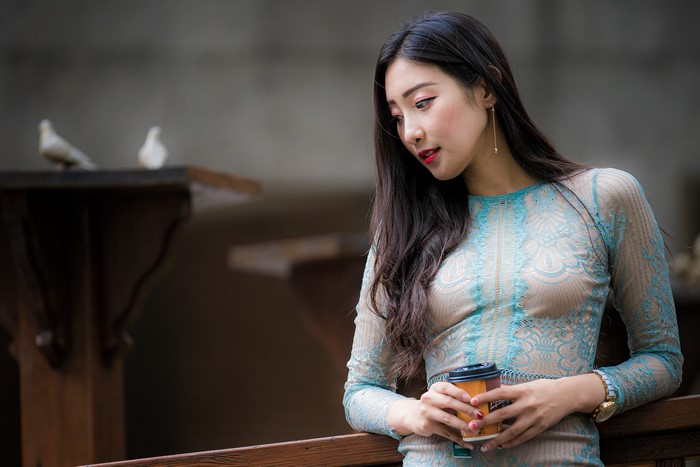 Asian woman in a blue lace dress holding a coffee cup