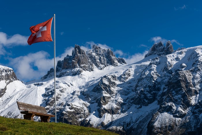 Switzerland flag and snowy Alps mountains
