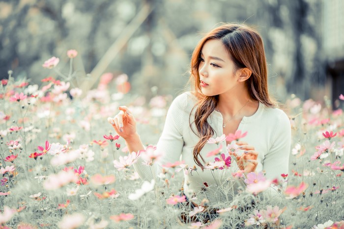 Asian woman with brown hair in a field of cosmos flowers